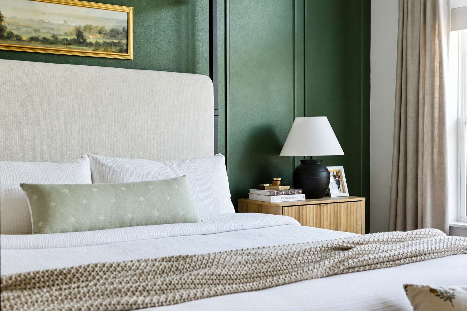 Primary bedroom with green paneled wall, upholstered headboard, wood nightstand, and black lamp