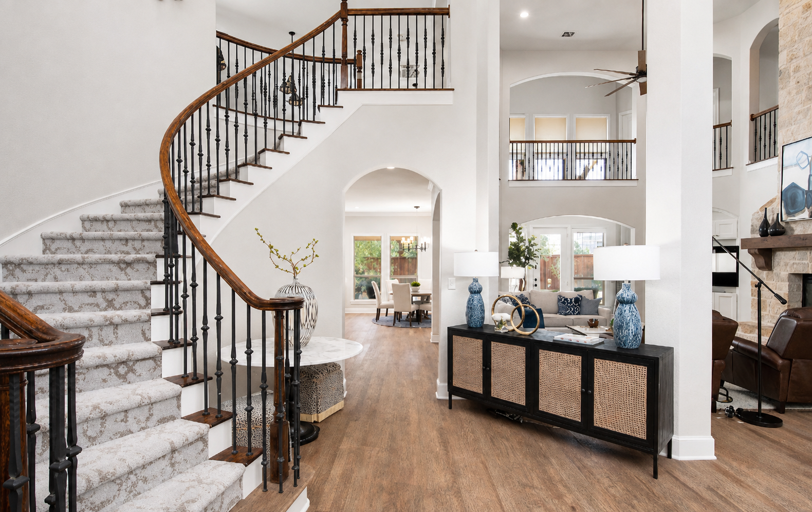 Grand two-story entryway with curved staircase, black console table, and open-plan living beyond